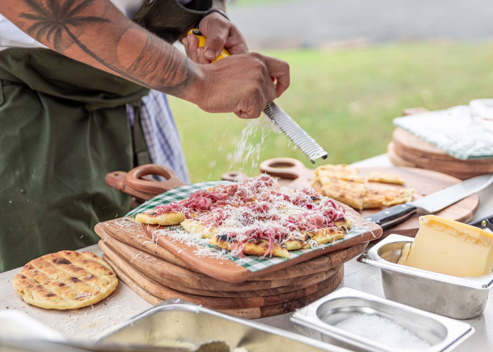 A chef grating cheese over grilled flatbread at Estancia Adina