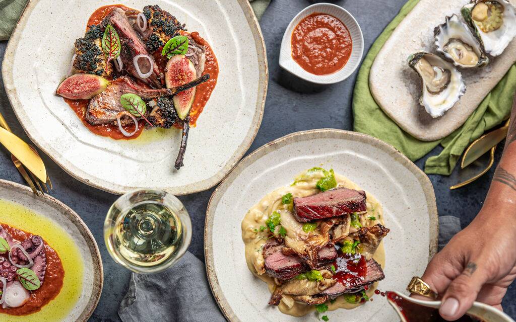 An overhead spread of shared plates, oysters and wine at Estancia Adina